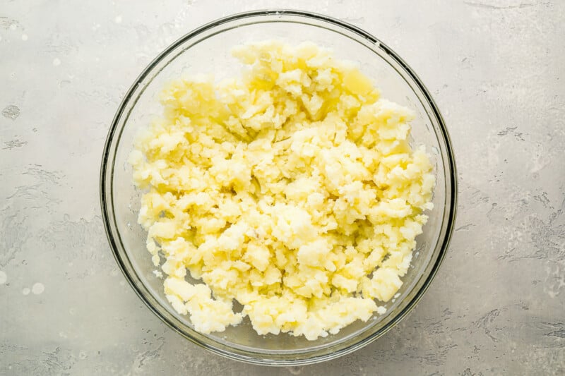 Butter in a glass bowl on a gray surface.