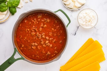 A pan of spaghetti sauce with cheese and basil.