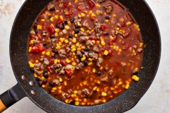 A frying pan filled with chili and corn.