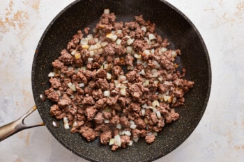 A frying pan with ground beef and onions.