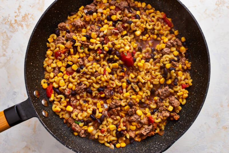 A frying pan filled with corn, meat and beans.