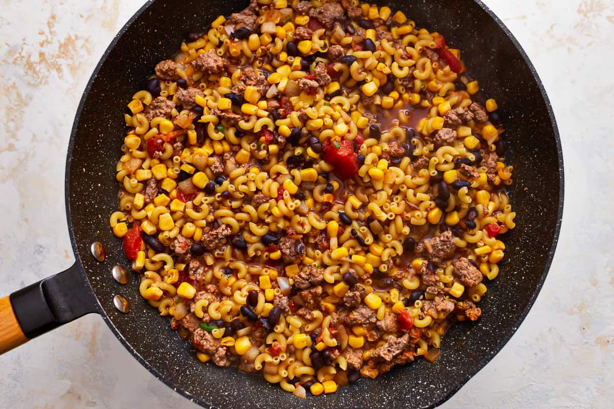 A frying pan filled with corn, meat and beans.