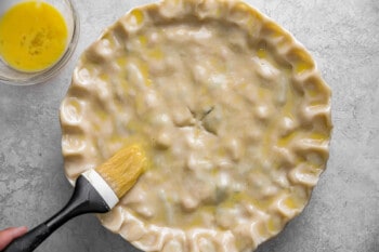 A person using a brush to make a pie crust.