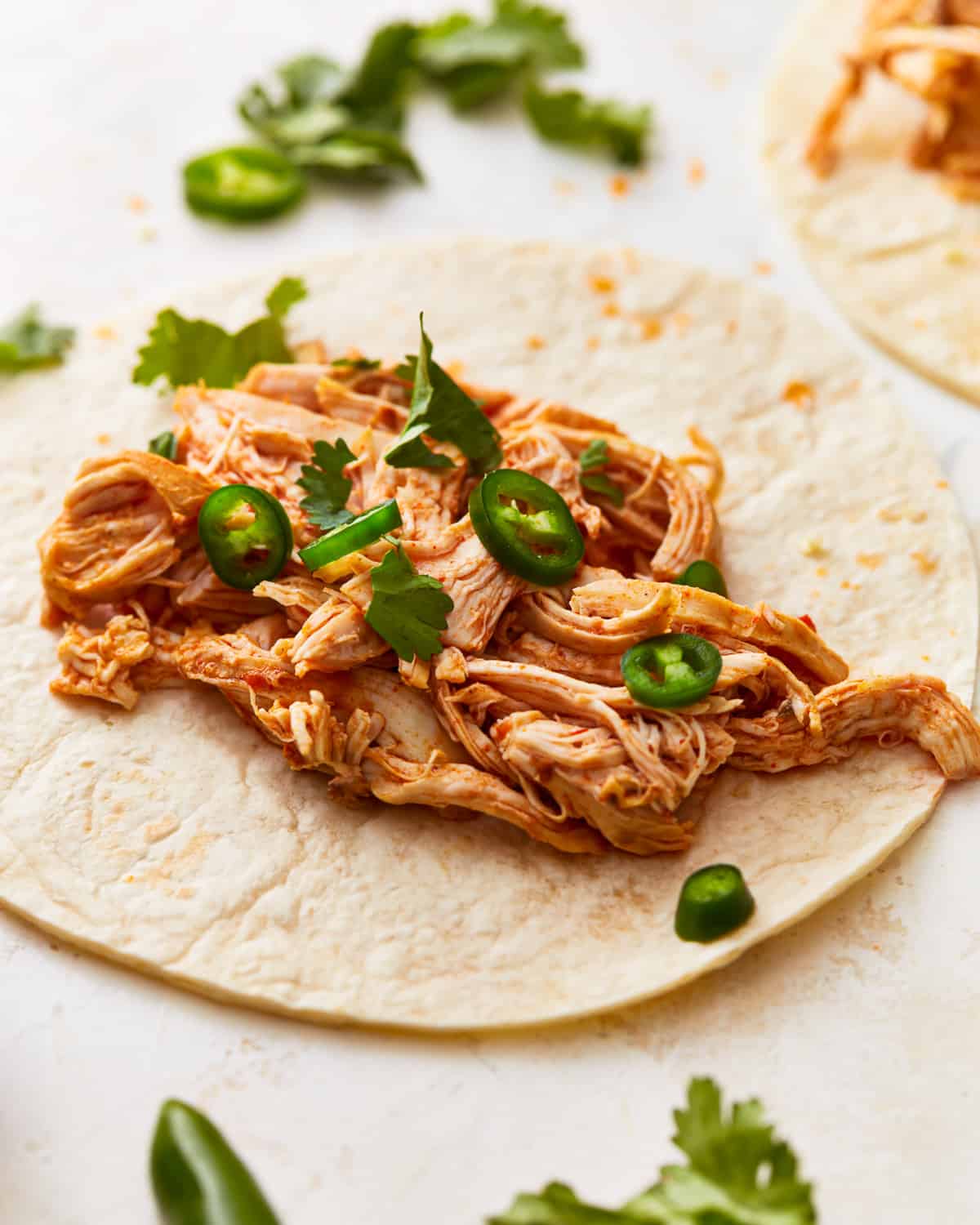 Pressure cooker shredded chicken spread on a tortilla.