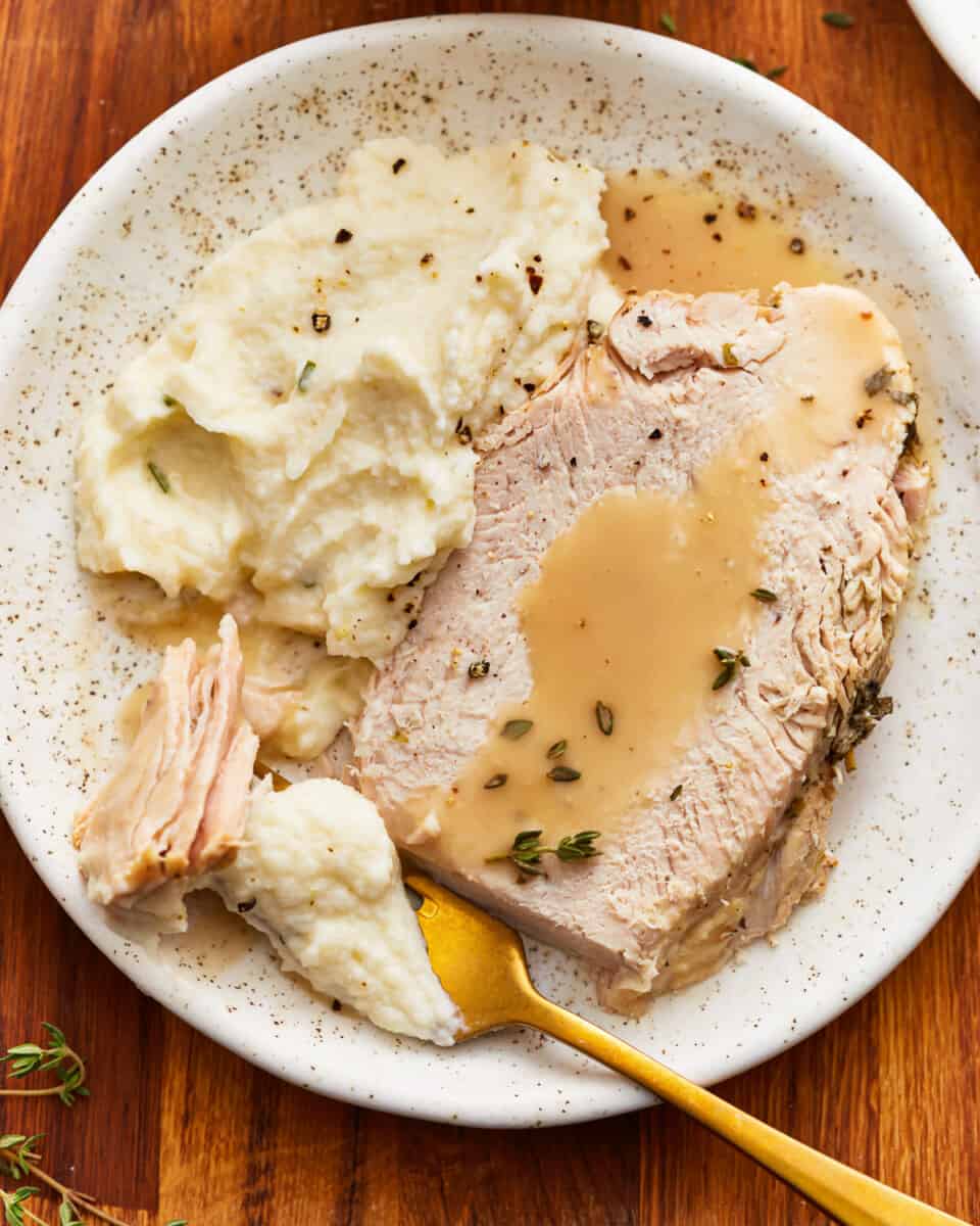 A plate of turkey with gravy and mashed potatoes.