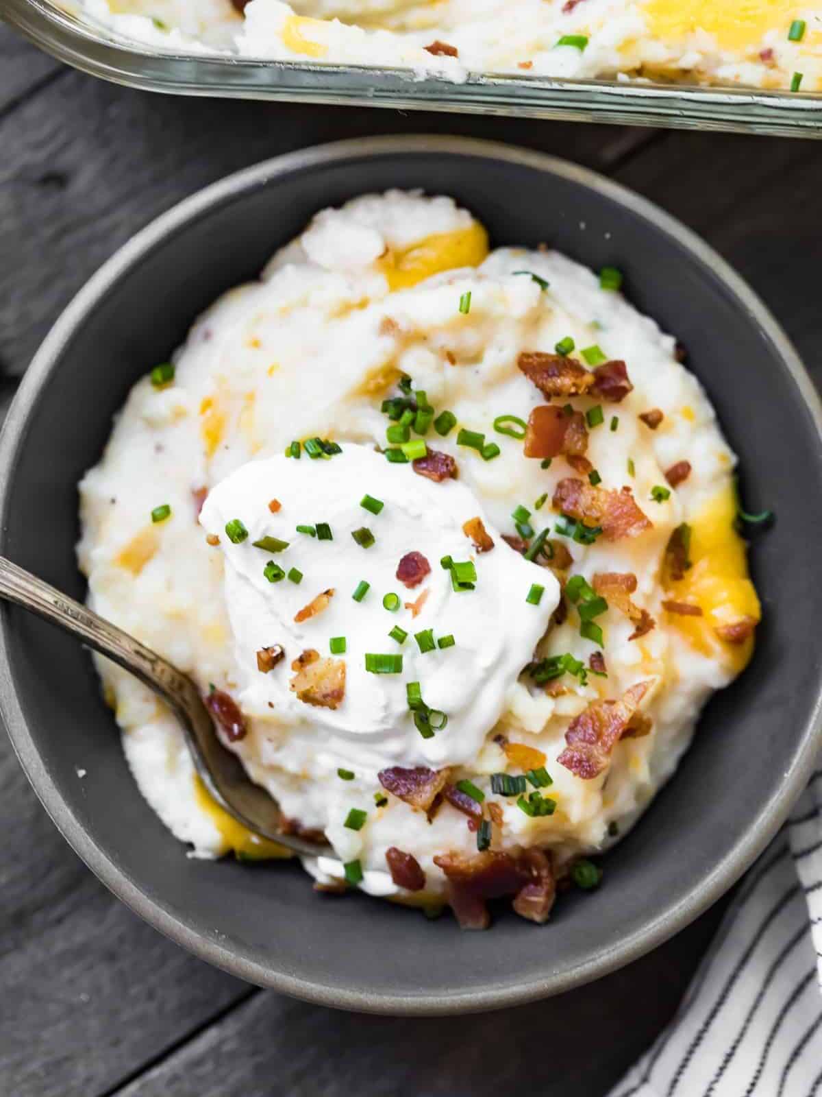 bowl of mashed potato casserole topped with sour cream