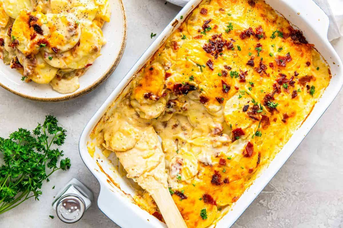 pan of loaded scalloped potatoes next to plate