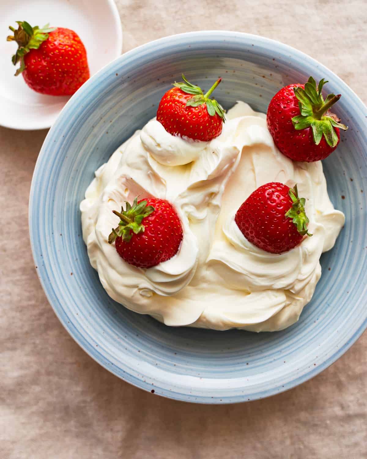 A blue plate with homemade mascarpone cheese and strawberries.