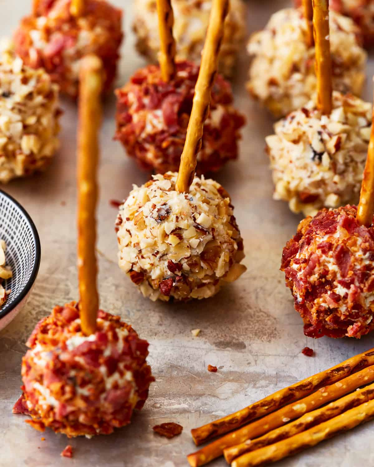 mini cheese ball bites with bacon and nuts on pretzel sticks.