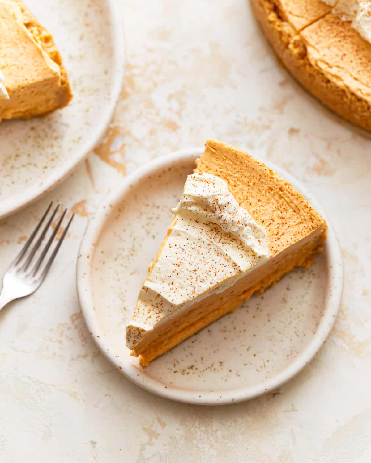 A slice of pumpkin pie cheesecake on a plate with a fork.