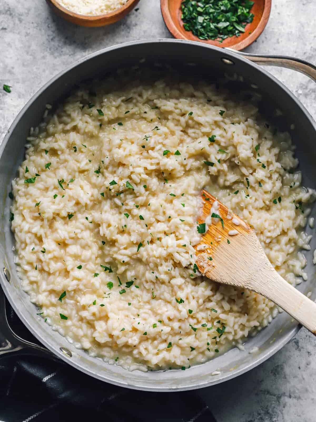 parmesan risotto in a sautépan with a wooden spoon.