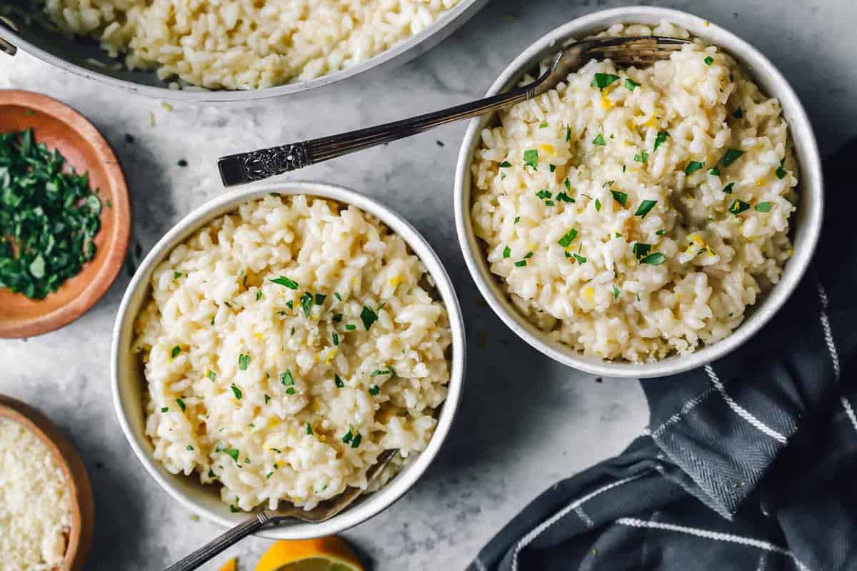 garlic parmesan risotto in white bowls with forks.