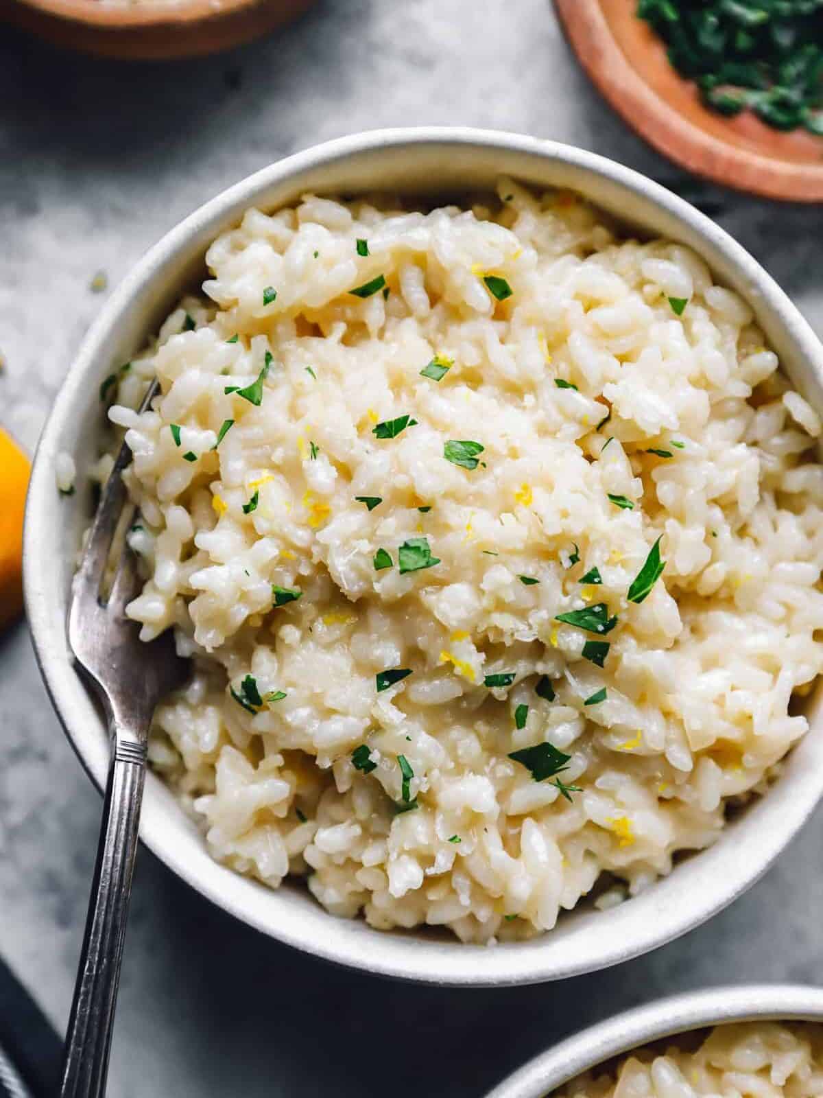 parmesan risotto in a white bowl with a fork.