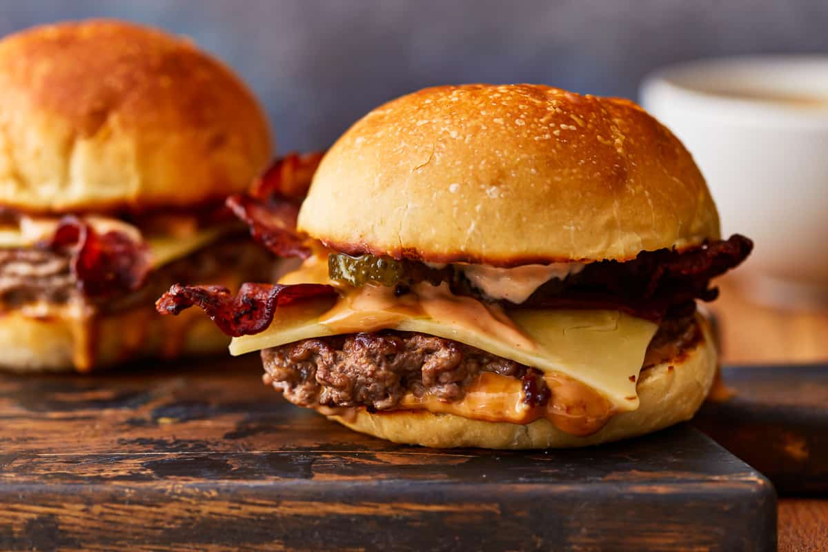 Two peanut butter bacon burgers on a cutting board.