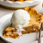 A slice of apple pie with ice cream on a plate.