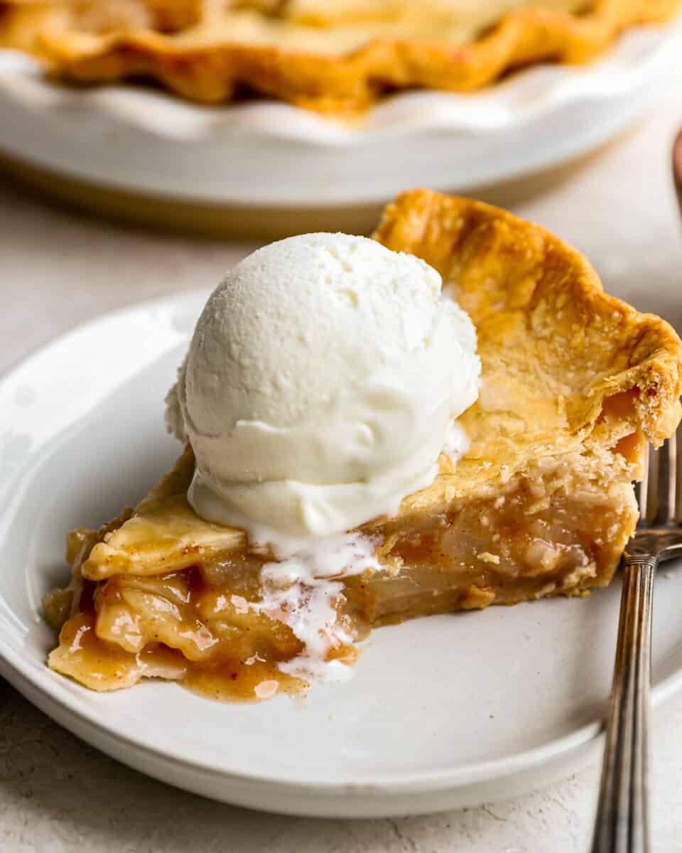 A slice of pear pie with ice cream on a plate.