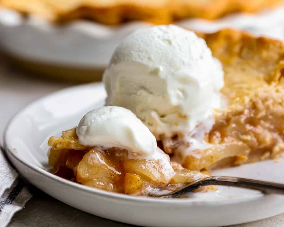 A slice of pear pie with ice cream on a plate.
