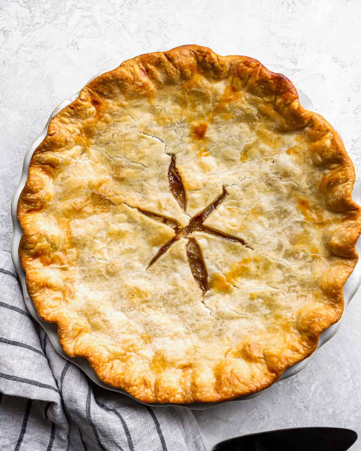 A homemade pie on a plate with a knife and fork.