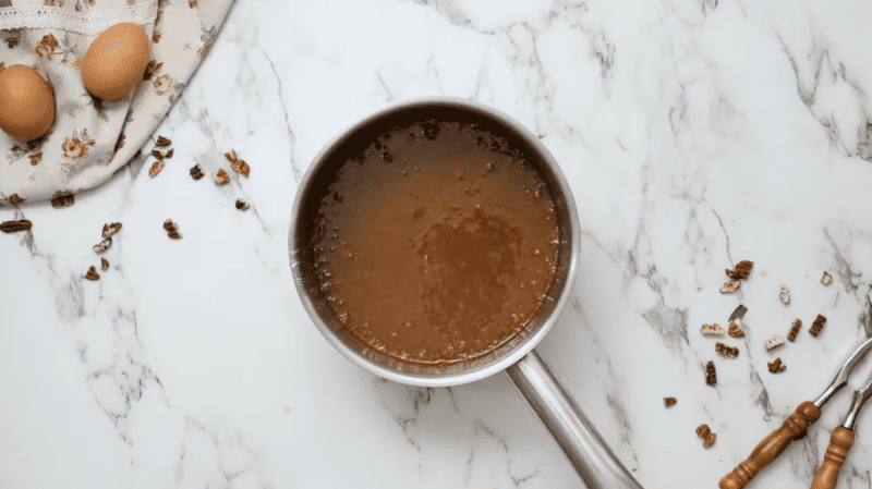 A Classic Pecan Pie with brown sauce and eggs on a marble countertop.