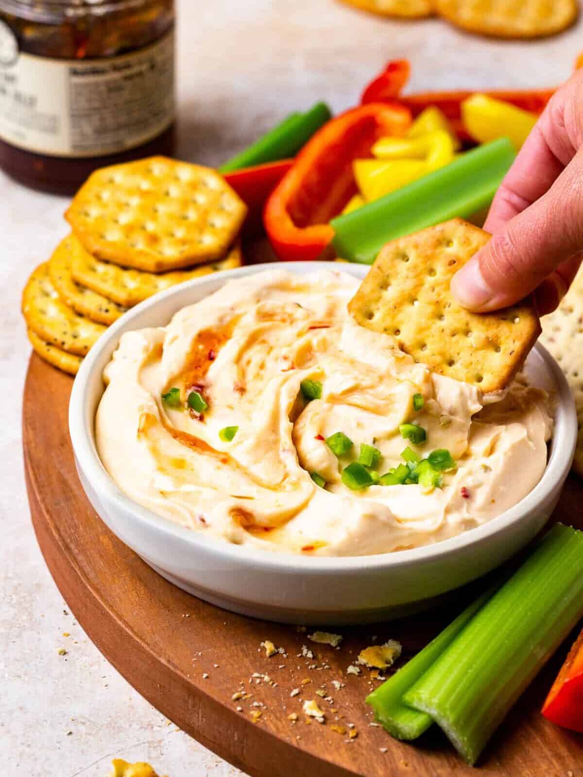 dipping a cracker into pepper jelly dip