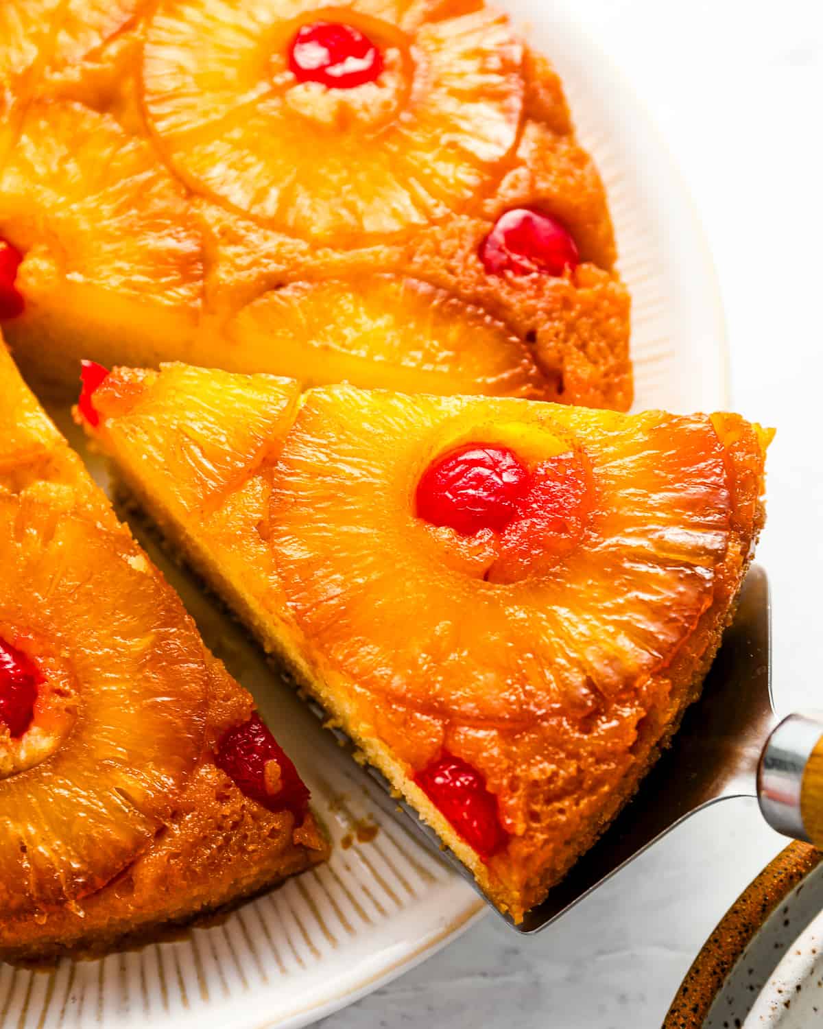 A slice of pineapple upside down cake on a plate.