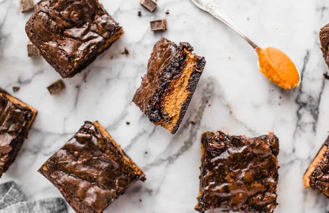 overhead view of brownies scattered on a marble countertop, one upturned to show a pumpkin layer.