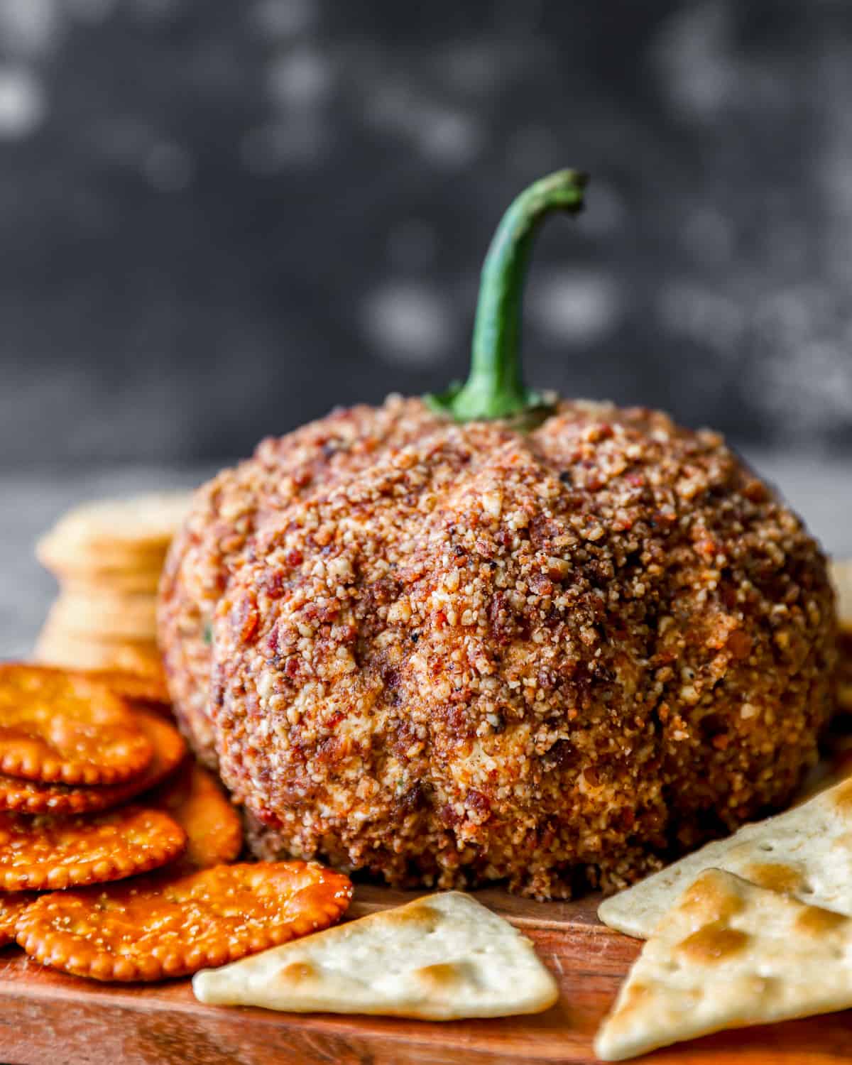 Pumpkin cheese ball on a wooden board with crackers.