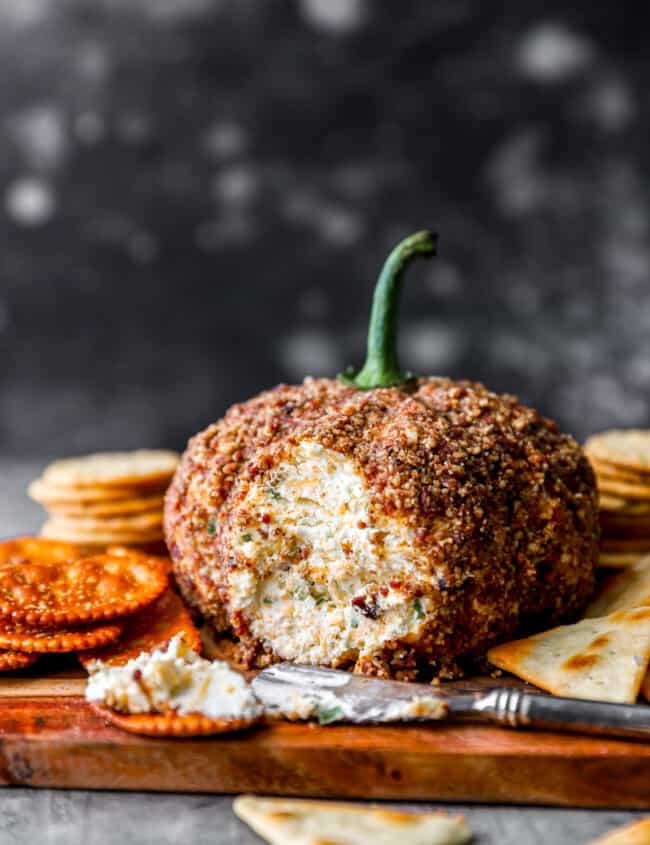 Pumpkin cheese ball on a cutting board with crackers.