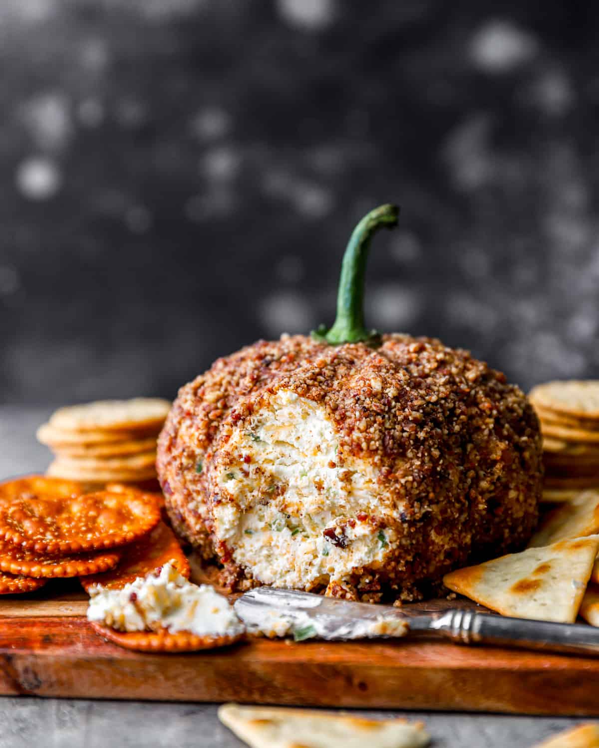 Pumpkin cheese ball on a cutting board with crackers.