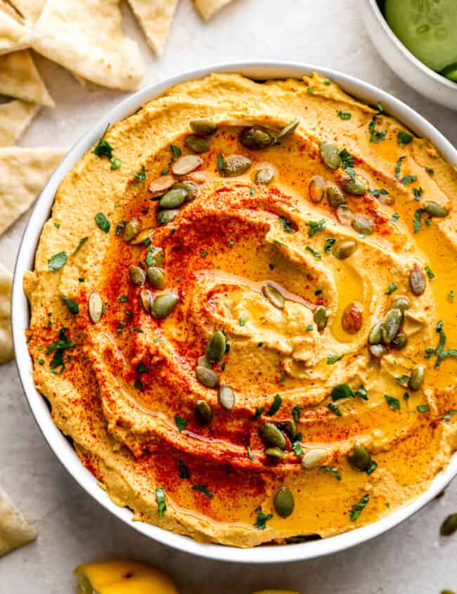 A bowl of hummus with pita chips.