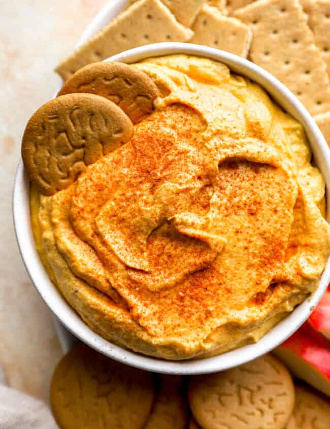 A bowl of pumpkin hummus with crackers and crackers.
