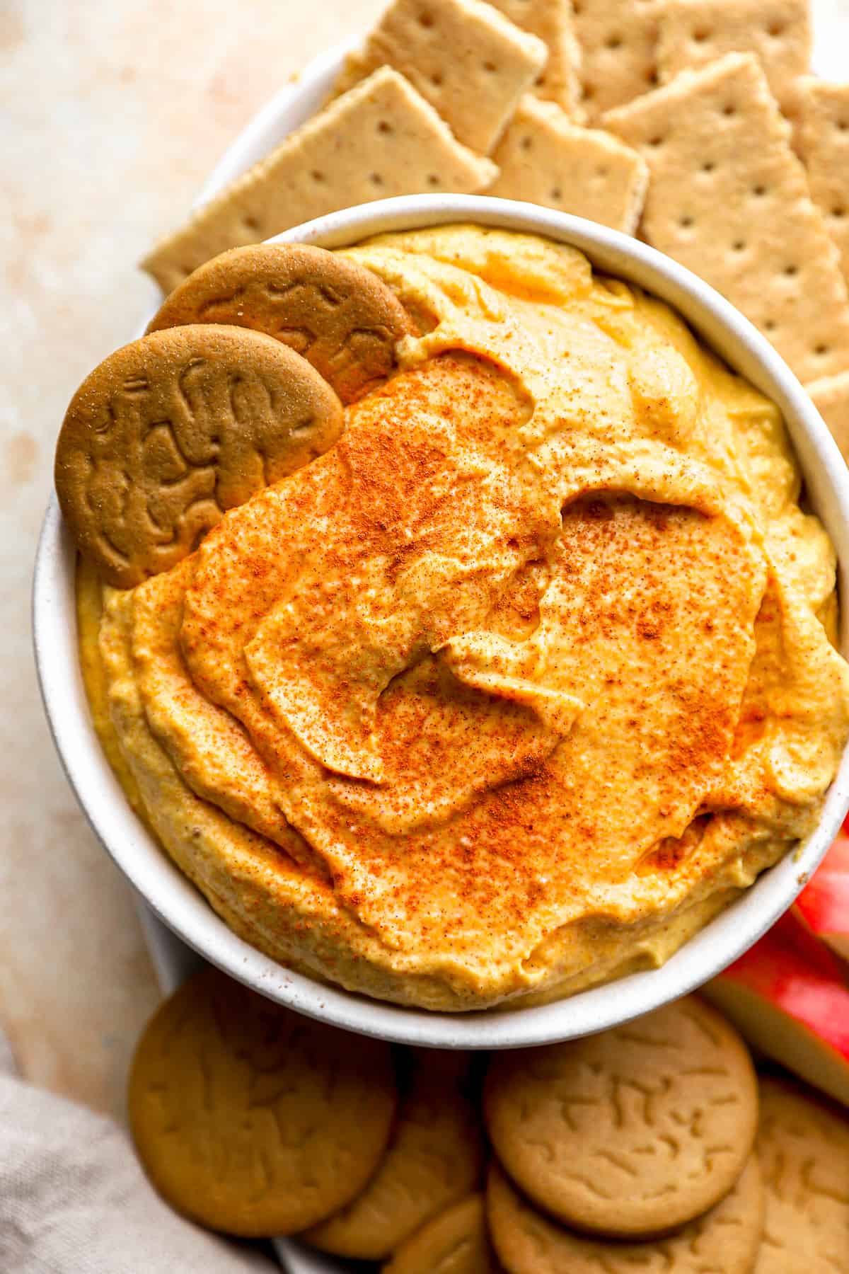 A bowl of pumpkin dip with cookies and crackers.