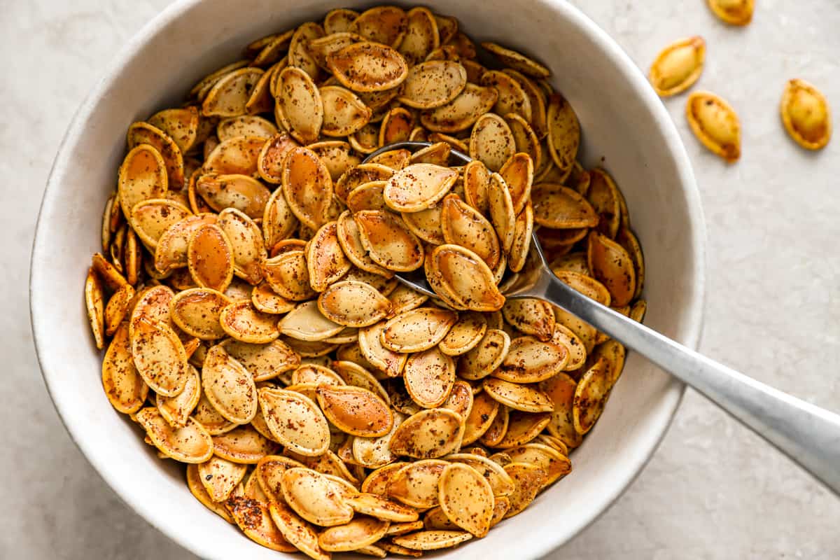 Pumpkin seeds in a bowl with a spoon.