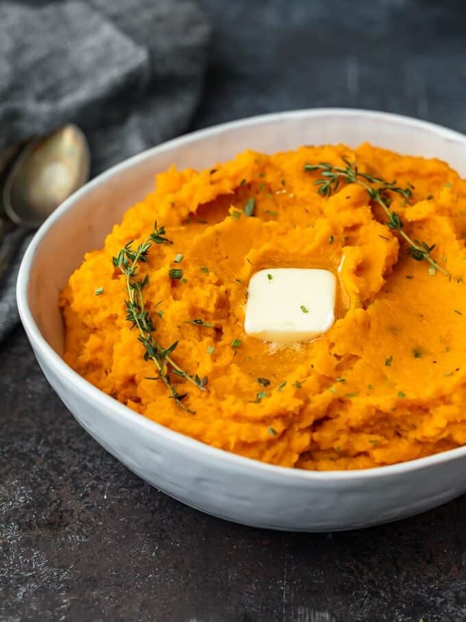a bowl of savory mashed sweet potatoes with sprigs of thyme.