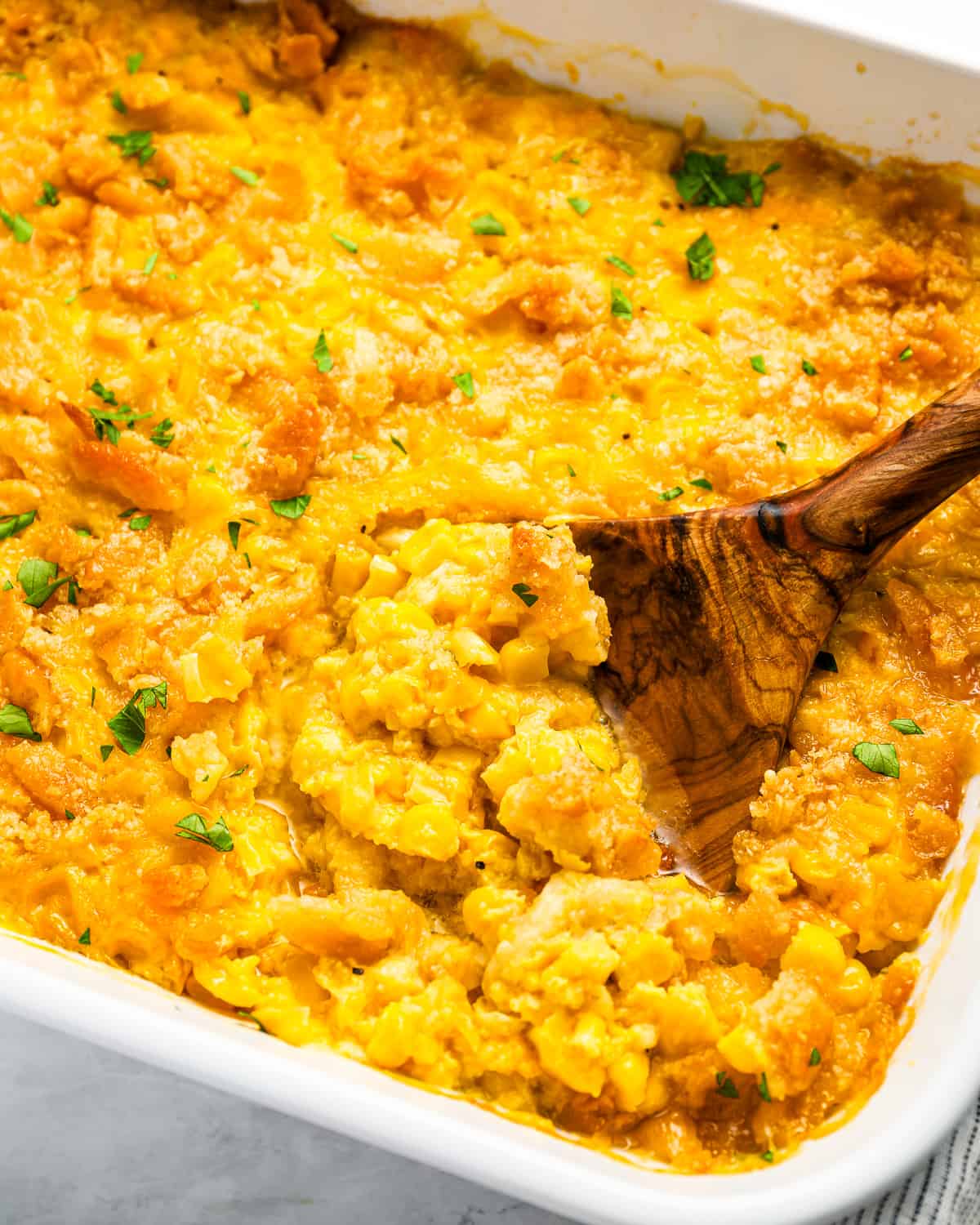 close up of scalloped corn in a casserole dish with a spoon.