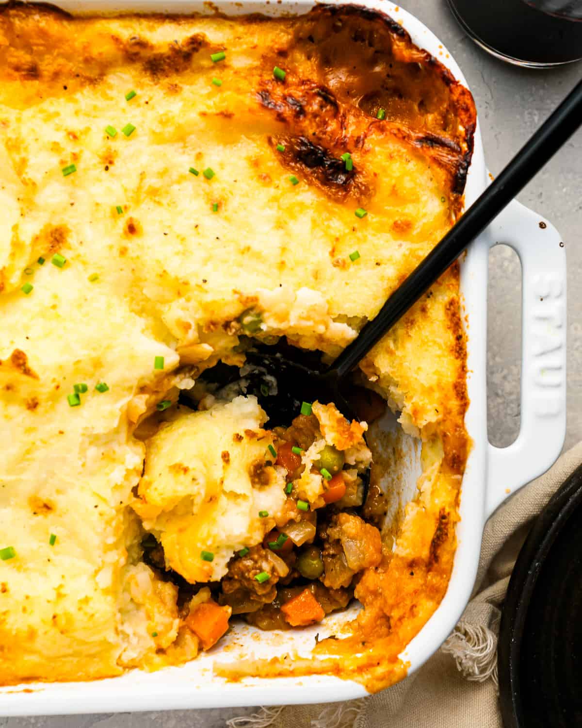 A casserole dish of shepherd's pie with a serving spoon in it.