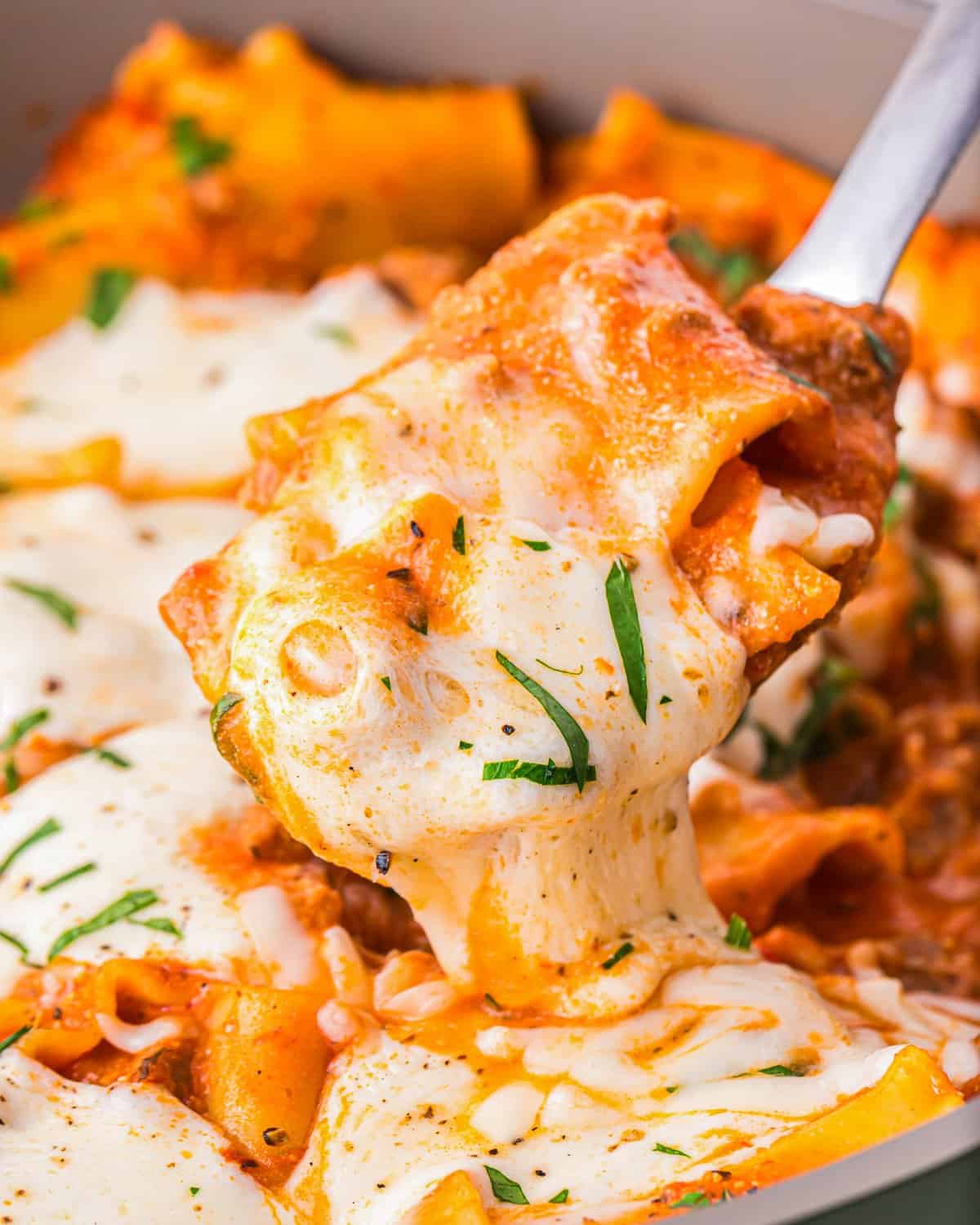 A spoon is being used to scoop up a serving of skillet lasagna.
