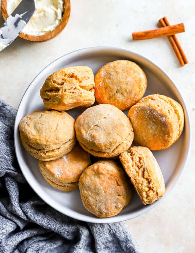 Pumpkin biscuits on a plate with cinnamon sticks.