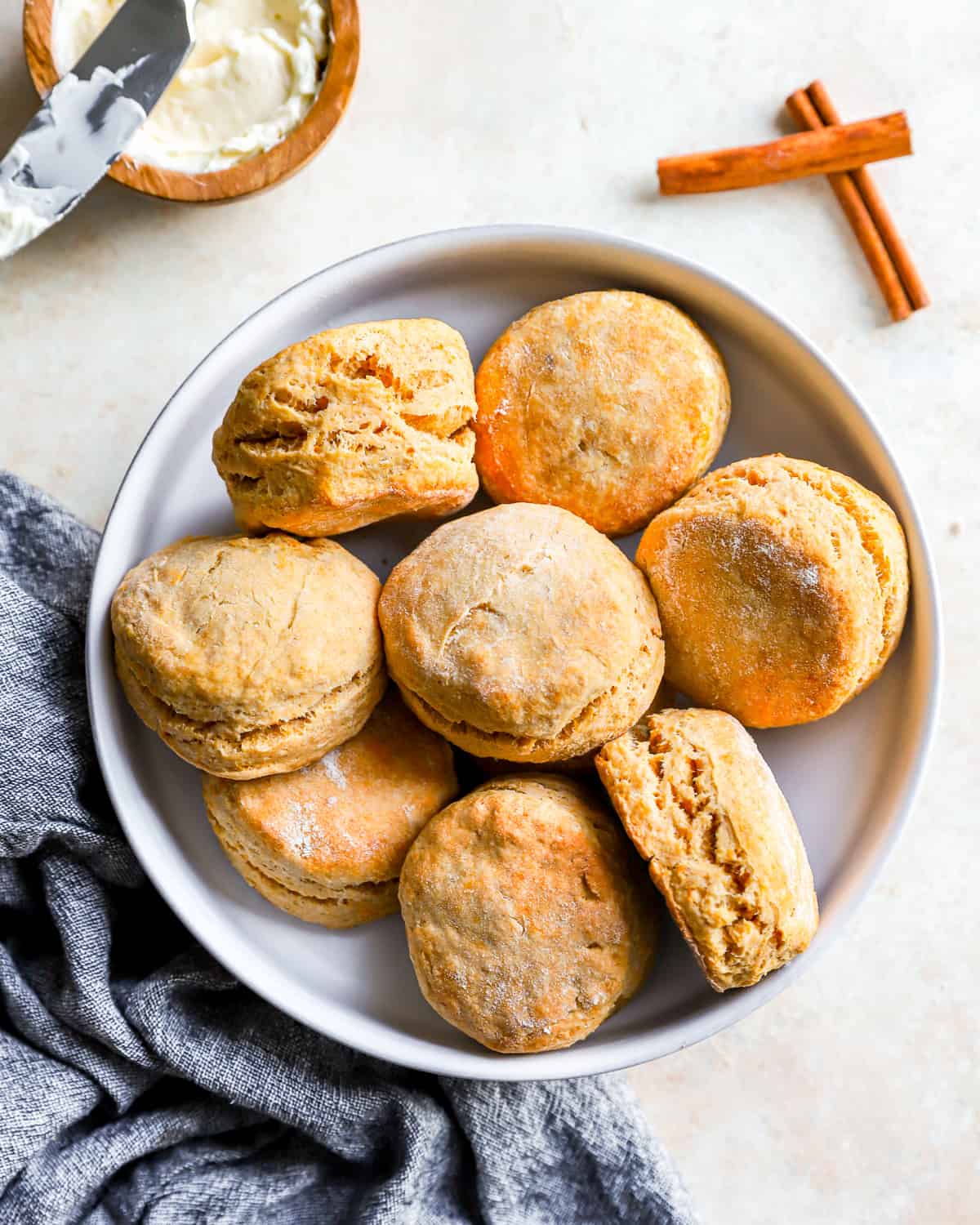 Sweet potato biscuits on a plate, next to cinnamon sticks.