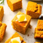 Cornbread squares with butter and honey on a plate.