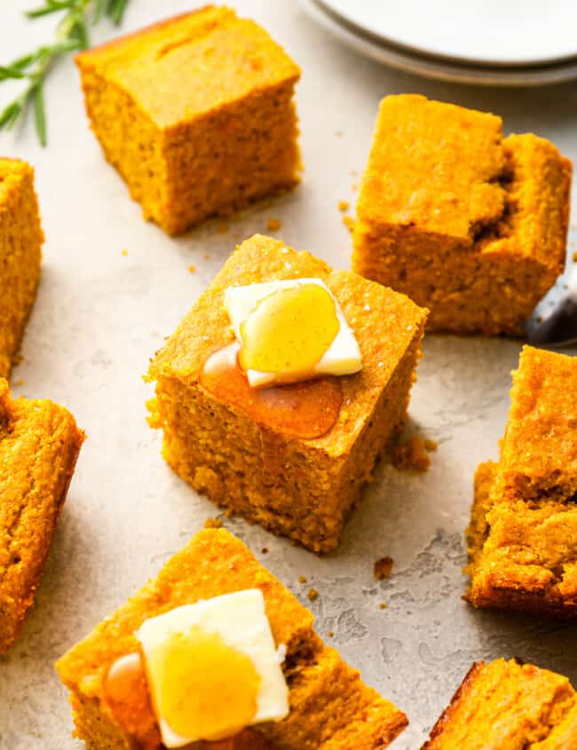 Cornbread squares with butter and honey on a plate.