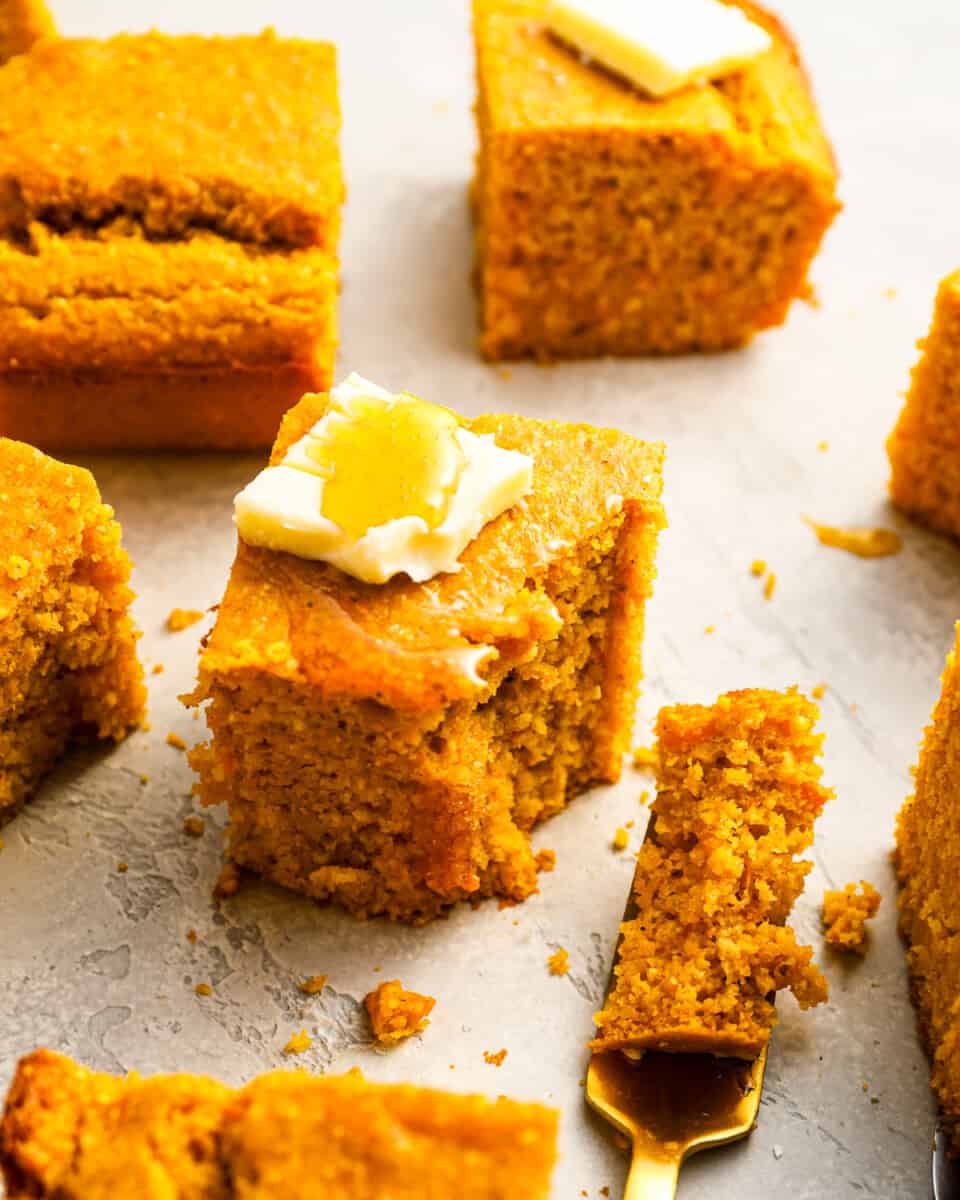 A group of pieces of sweet potato cornbread with butter on top.