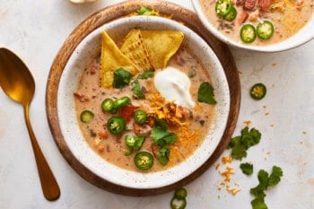 Two bowls of chili with tortilla chips and sour cream.