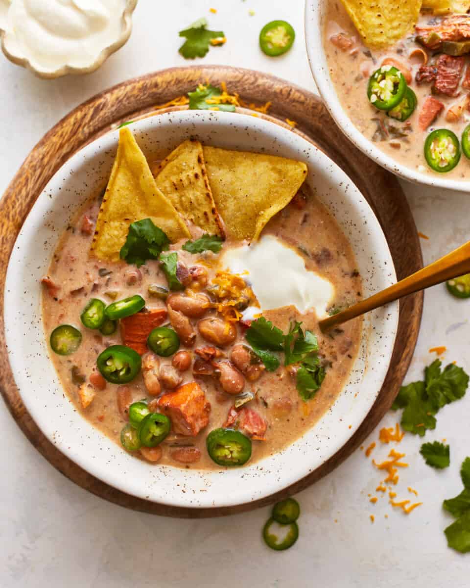Two bowls of chili with tortilla chips and sour cream.