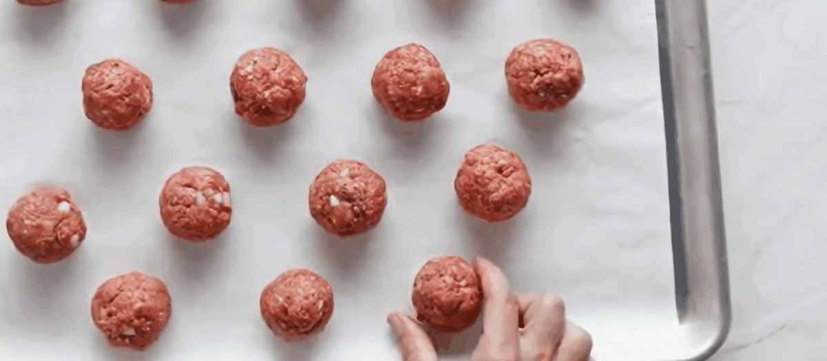 Meatballs on a parchment lined baking sheet. 