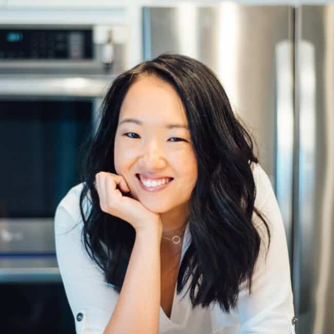 An Asian food blogger smiling in a kitchen.