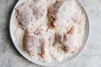 chicken thighs coated in a flour mixture in a white bowl