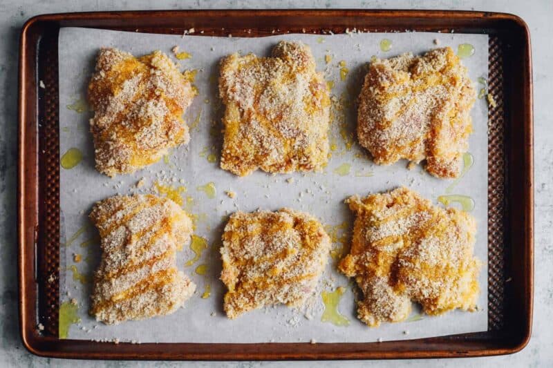 chicken thighs on a parchment paper lined baking sheet before baking