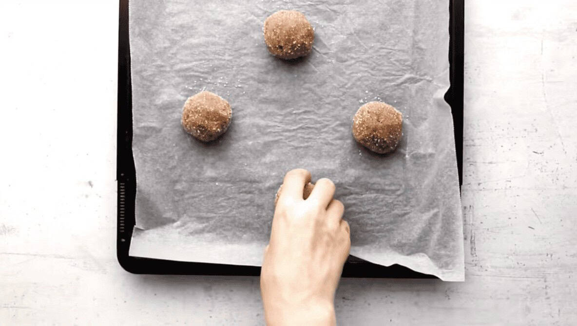 Molasses cookie dough balls on a parchment lined cookie sheet.