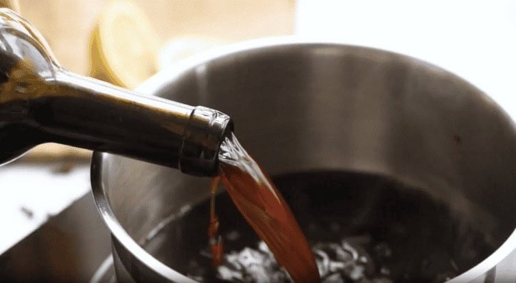 Pouring red wine into a pot. 
